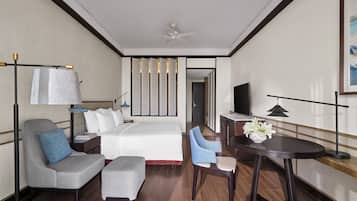 Une chambre d’hôtel équipée d’un lit, d’un bureau, d’une chaise, d’une télévision et d’un ventilateur de plafond.
