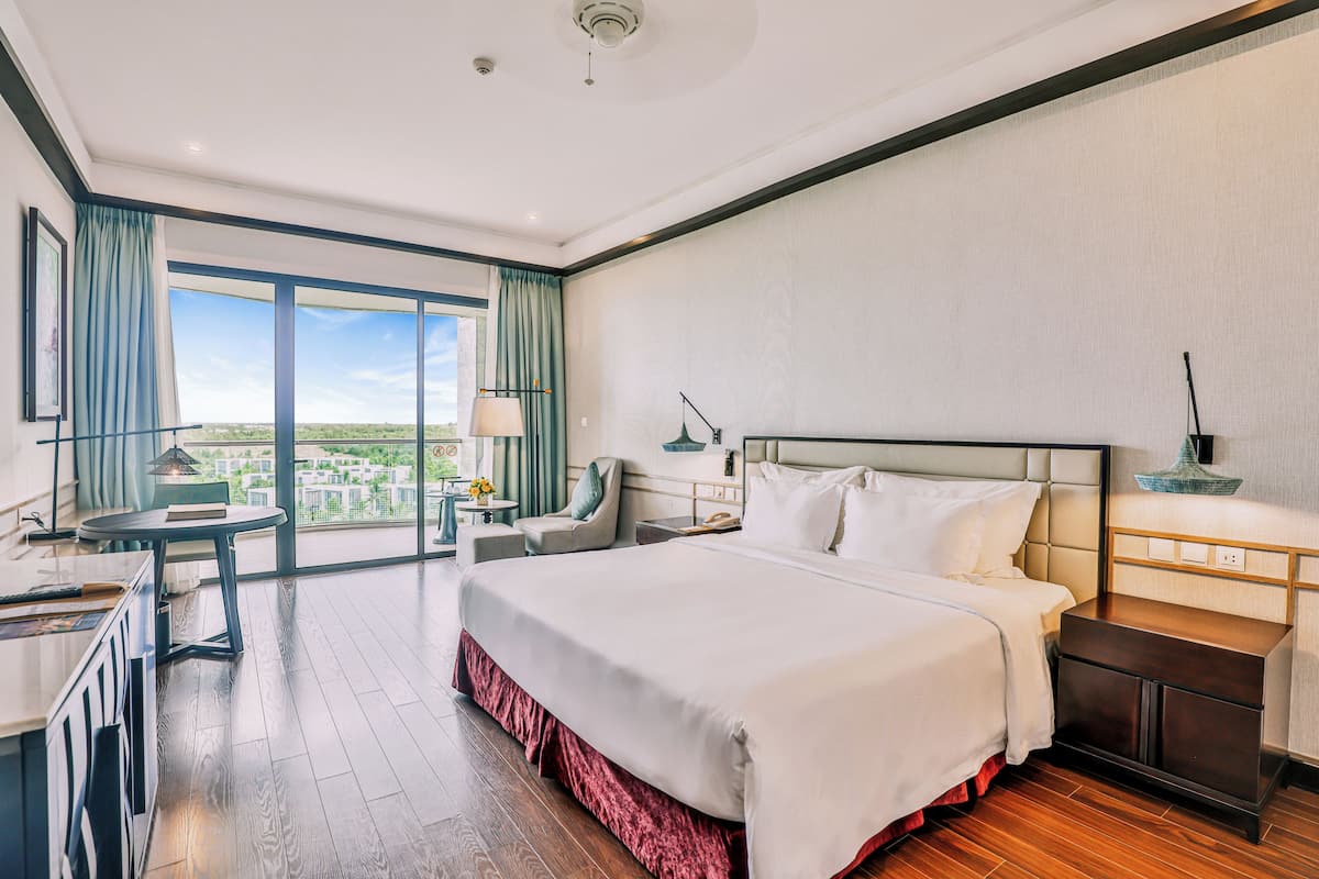 Une chambre d’hôtel avec un grand lit, un bureau, une chaise et une vue sur la ville.