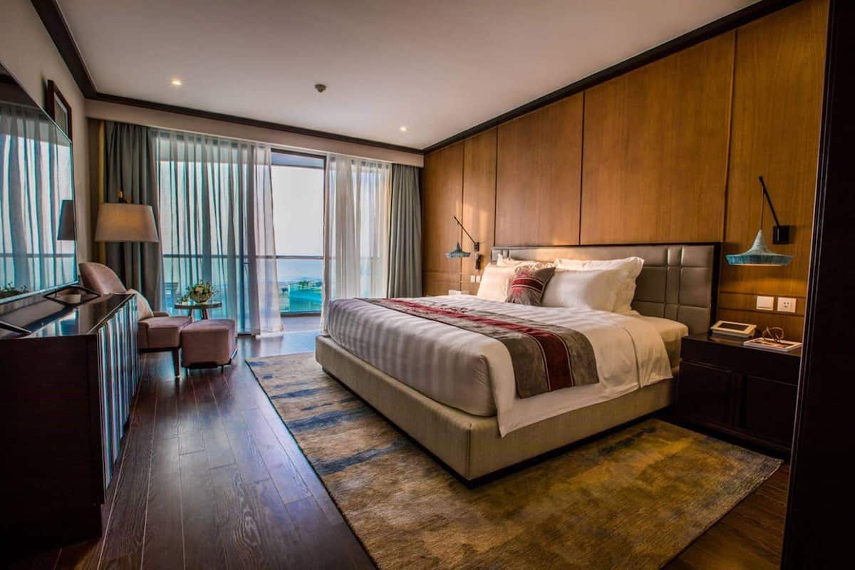 Une chambre d’hôtel moderne, dotée d’un grand lit, d’un bureau et offrant une vue sur l’extérieur.