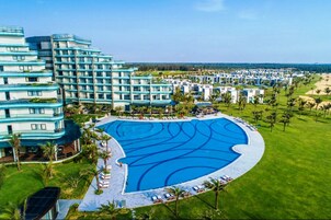 A resort with a large swimming pool, multiple hotel buildings, and a well-maintained lawn.
