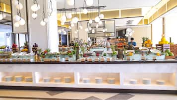 Zona de bufé con diversas opciones de comida y una cocina al fondo.