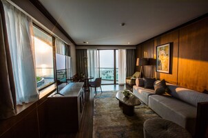 Habitación de hotel moderna con un ventanal grande, un sofá, una mesa de comedor y vistas al exterior.
