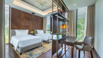 A hotel room with two beds, a desk, a chair, a ceiling fan, and a large window with blinds.