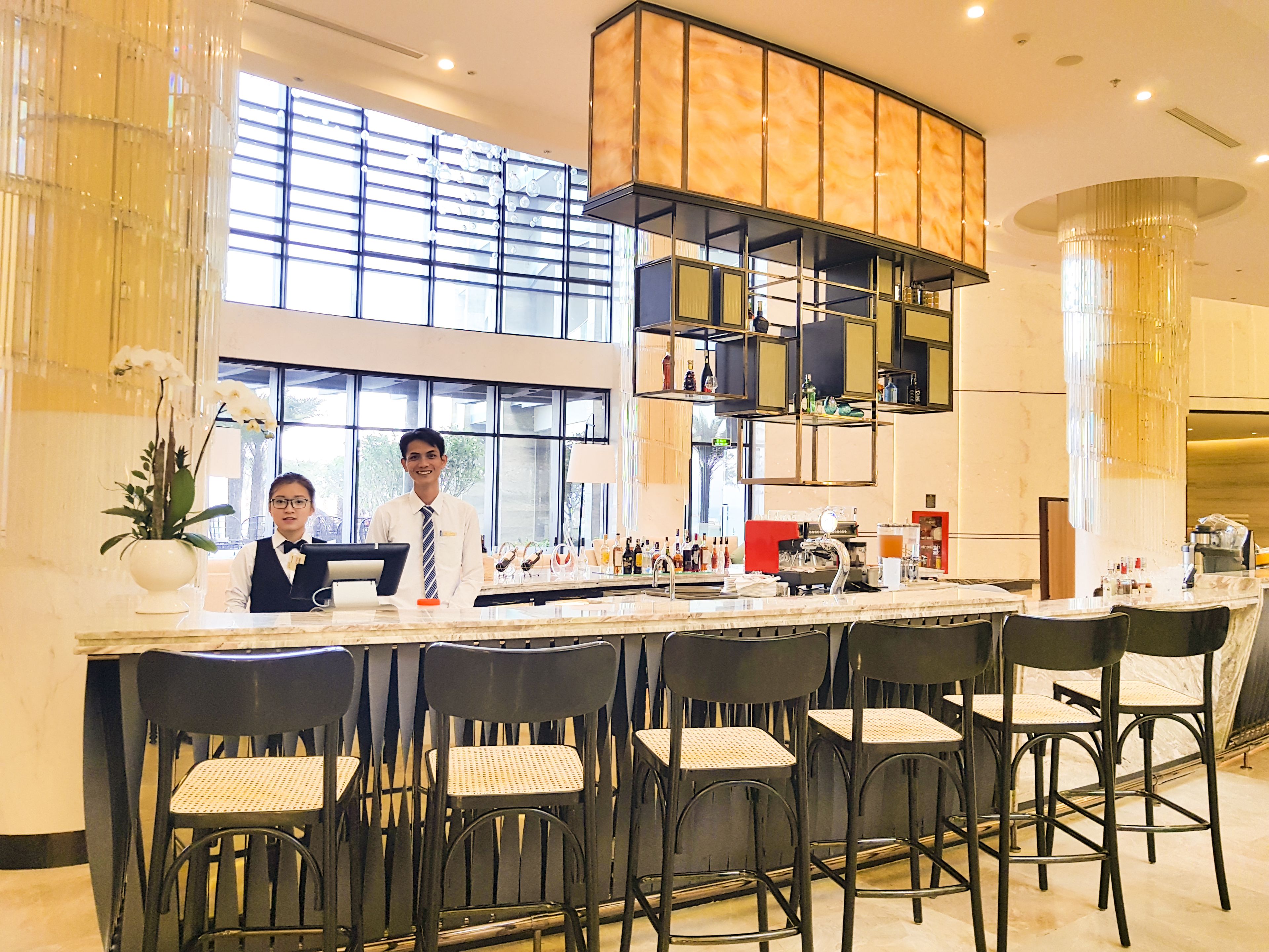 A bar area with a high counter, multiple chairs, and a bartender.