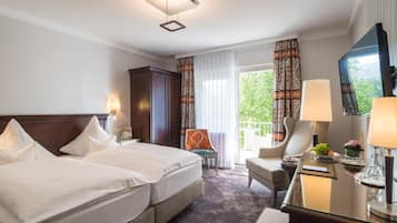 A hotel room with two beds, a desk, a chair, a TV, and a balcony with curtains.