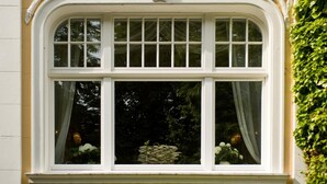 Une fenêtre sur laquelle on peut lire l’inscription « Villa Aurora », le tout encadré de motifs décoratifs représentant des feuilles.