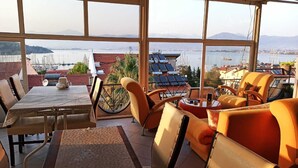 A terrace with a table and chairs, a view of the sea, and solar panels. - Ideal Pansiyon (Fethiye)