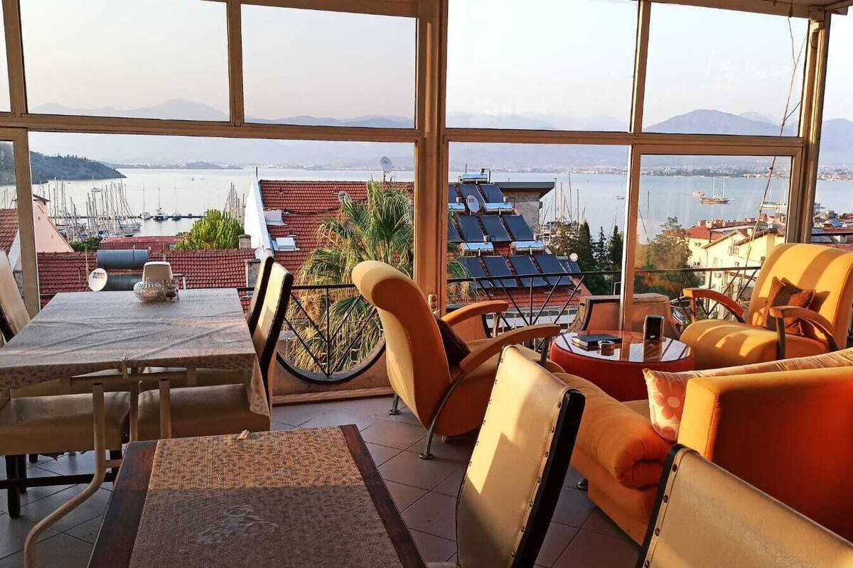 Een terras met een tafel en stoelen, een uitzicht op zee, en zonnepanelen.