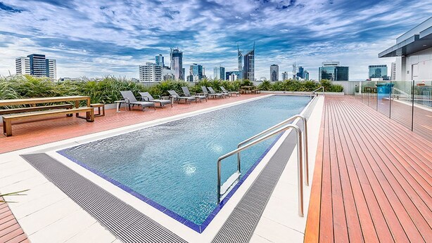 A rooftop pool with lounge chairs and a city skyline view. - The William Suites (Melbourne)