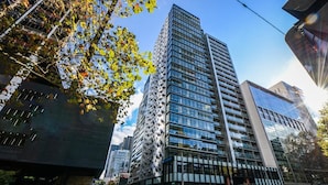 A modern high-rise building with a unique facade featuring geometric patterns. - The William Suites (Melbourne)