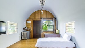 Une chambre avec deux lits, un radiateur, une télévision et une fenêtre avec des rideaux.