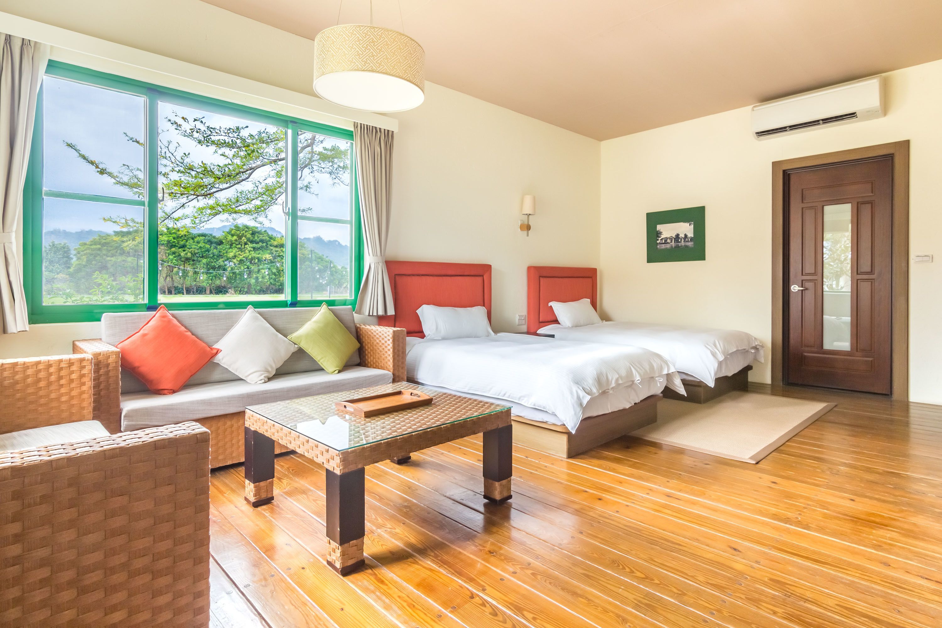 Habitación de hotel con dos camas, un sofá, una mesa y vistas a zonas verdes.