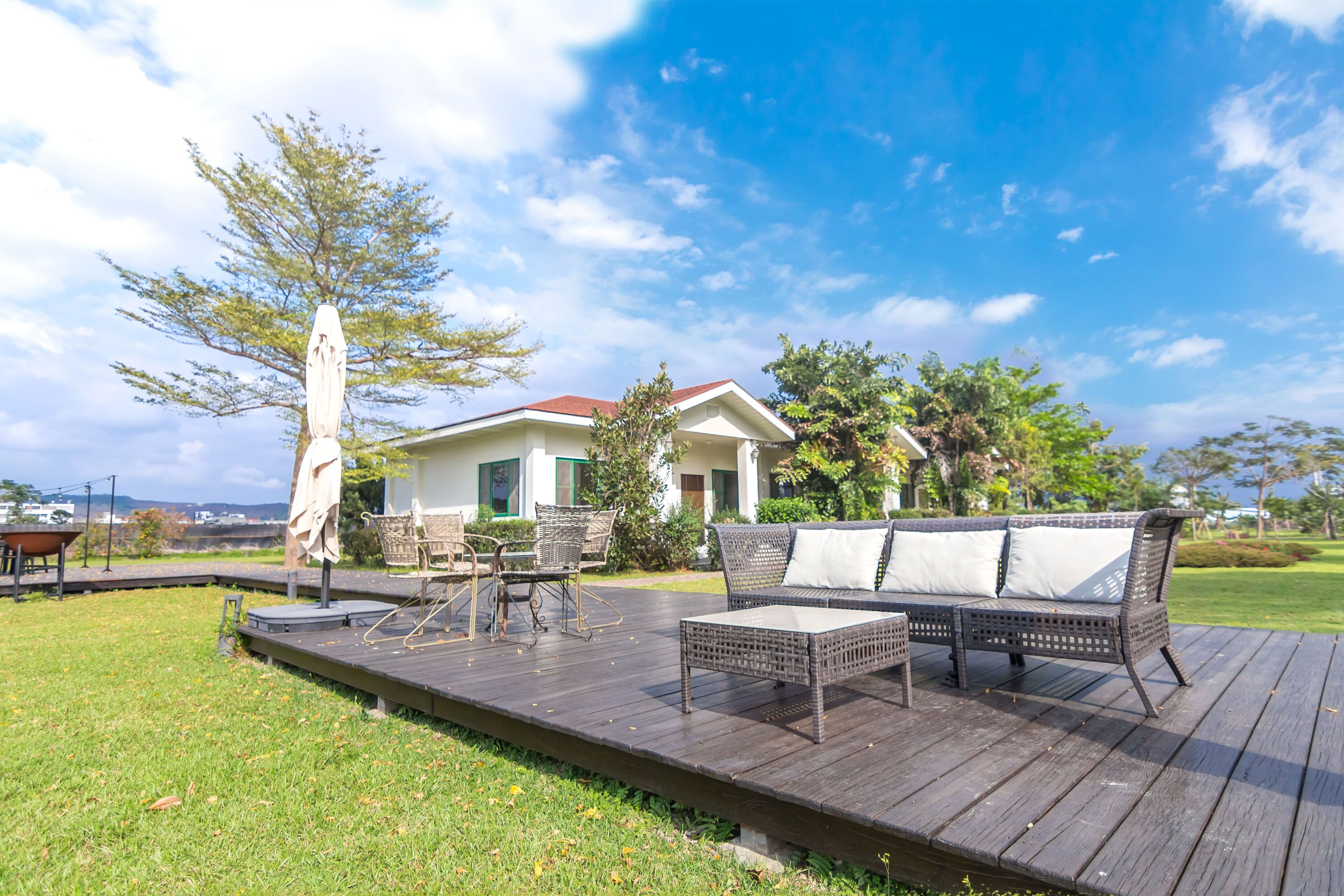 A deck with outdoor furniture, a pergola, and a house in the background.