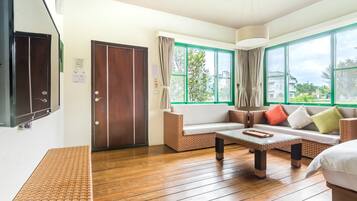 Una habitación con piso de madera, un sofá, una mesa de centro y una cama.