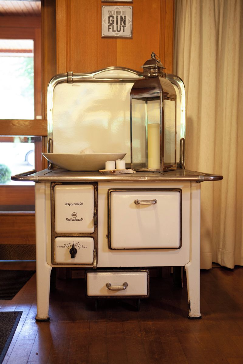 A vintage stove with a glass top, a candle holder, and a sign above it.