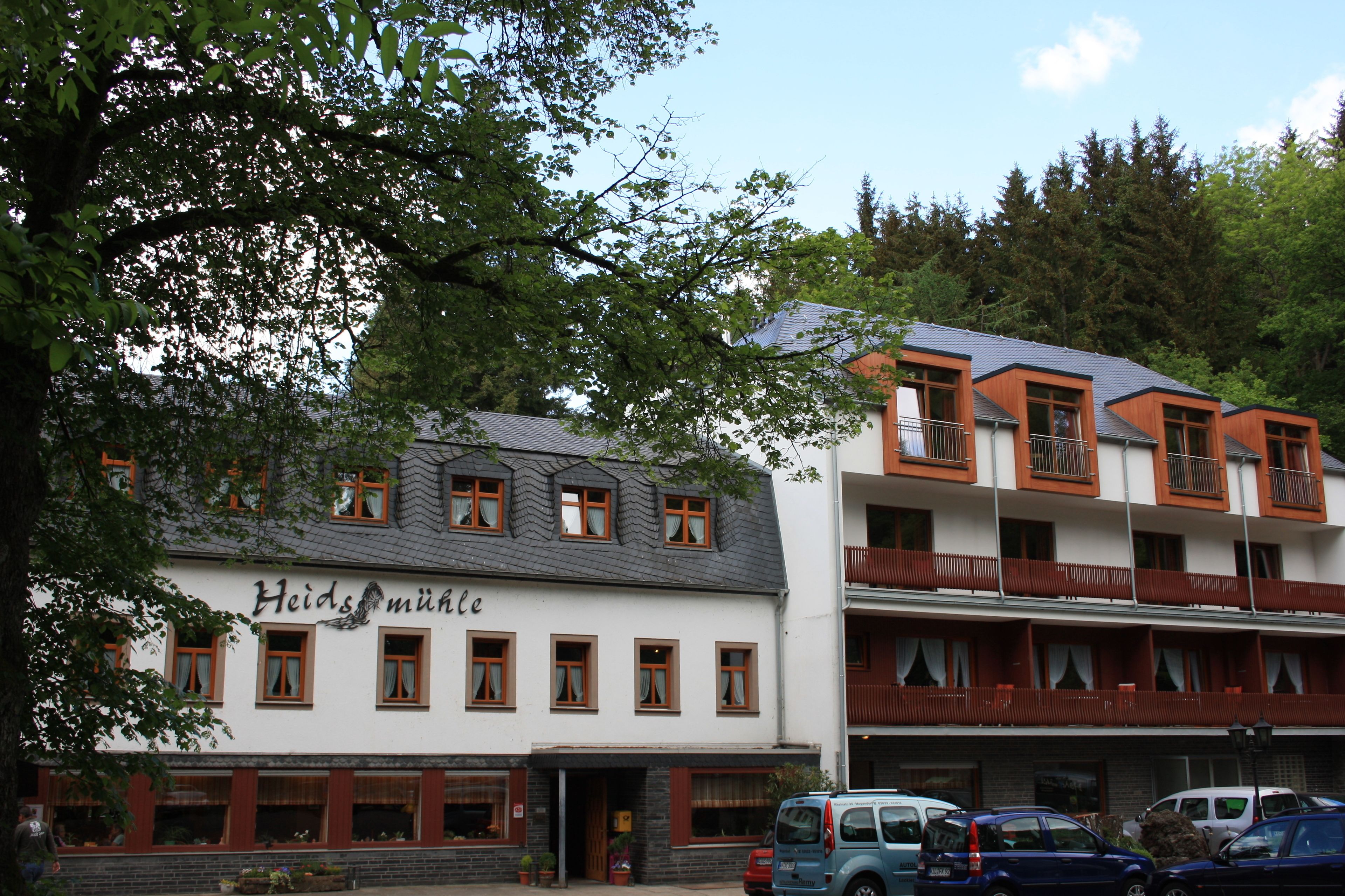 A building with a sign reading "Heids Mühle" and multiple windows with brown frames.