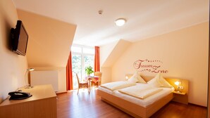 Una habitación de hotel moderna con una cama grande, un escritorio con teléfono, una silla, una mesa con planta y una ventana con cortinas.