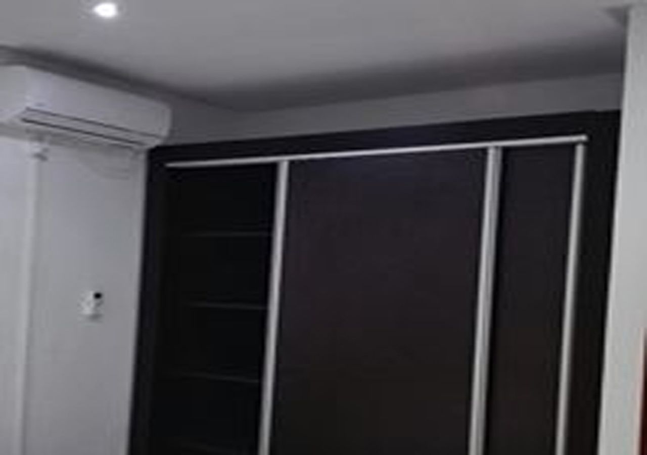 Una habitación con un armario oscuro, una pared blanca y una luz en el techo.