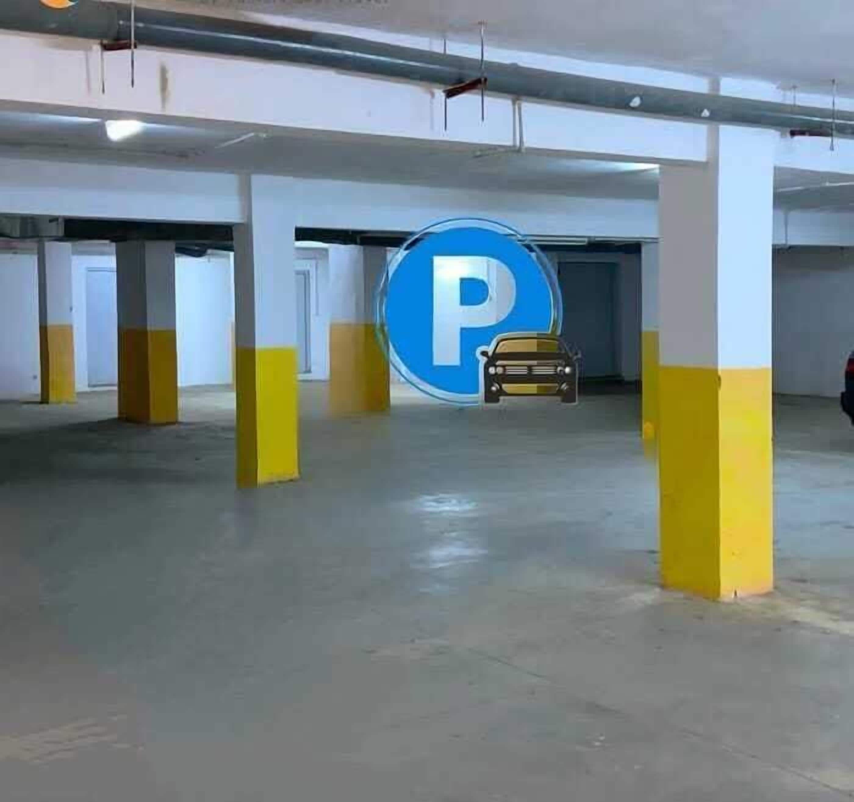 Un aparcamiento con pilares amarillos, un cartel azul grande con la letra 'P' y un coche a lo lejos.