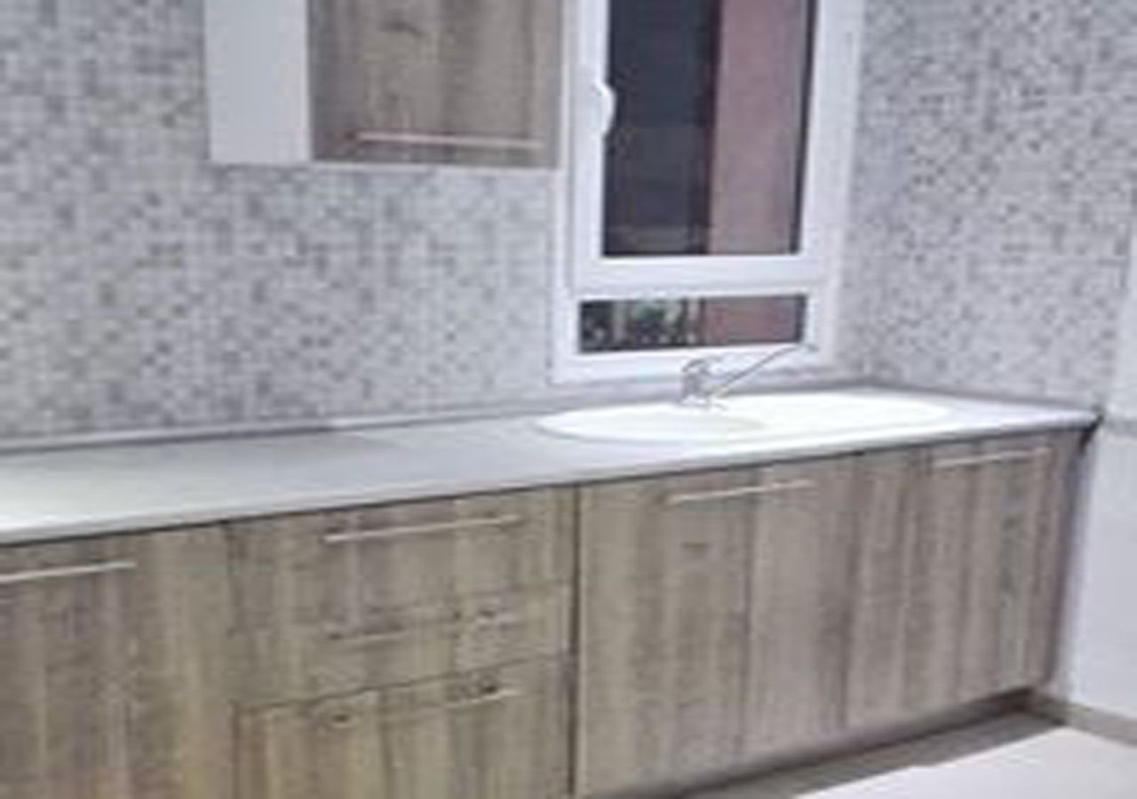 Un bagno con lavandino bianco, mobiletti in legno e una finestra.