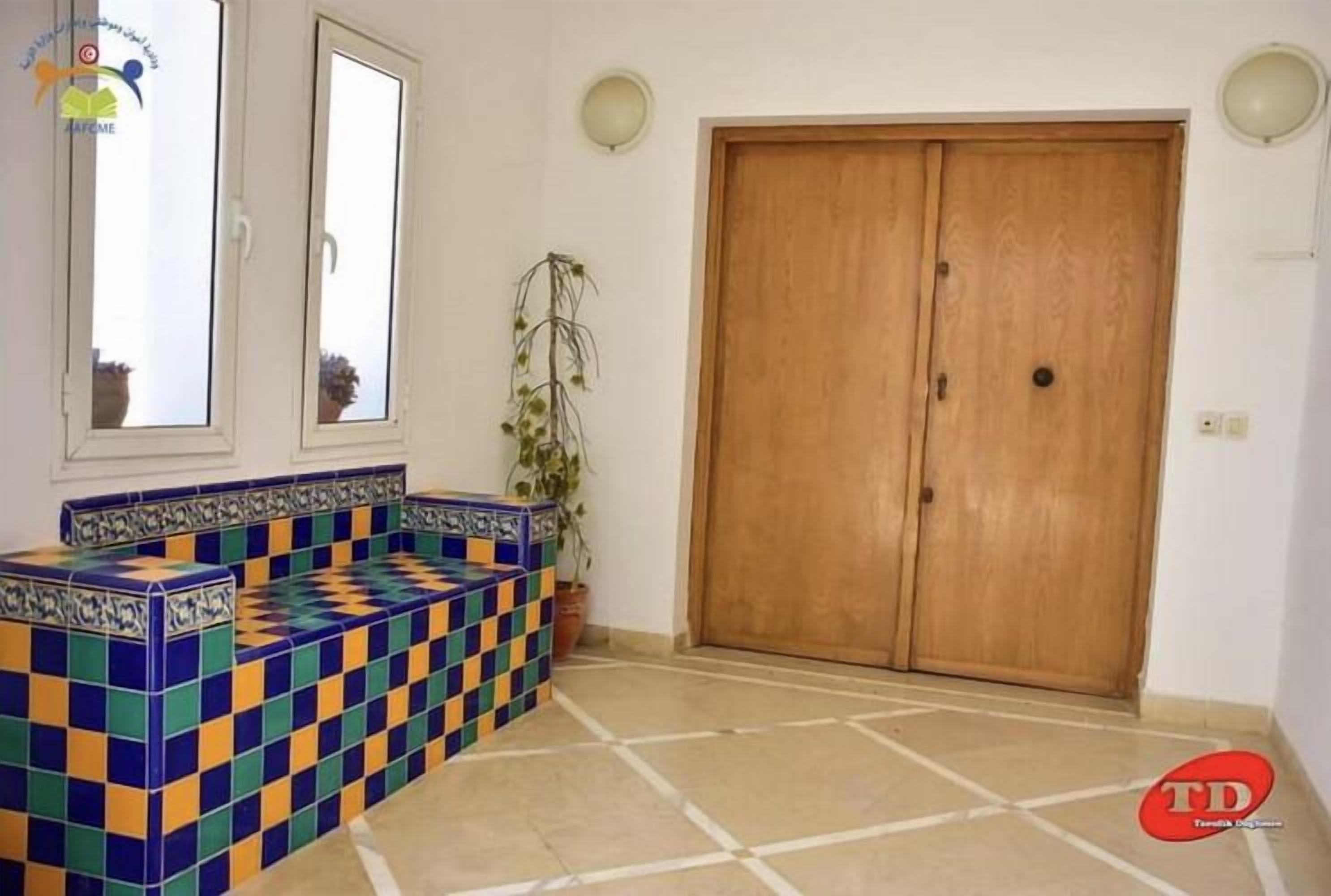 A room with a tiled bench, a wooden door, and a potted plant.