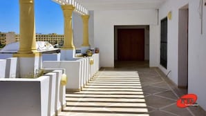 A corridor with white walls and yellow columns, leading to a door. - Residence Aladin (Hammamet)