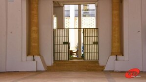 A spacious entrance with a staircase leading to a balcony, featuring a metal gate and a view of buildings in the background. - Residence Aladin (Hammamet)