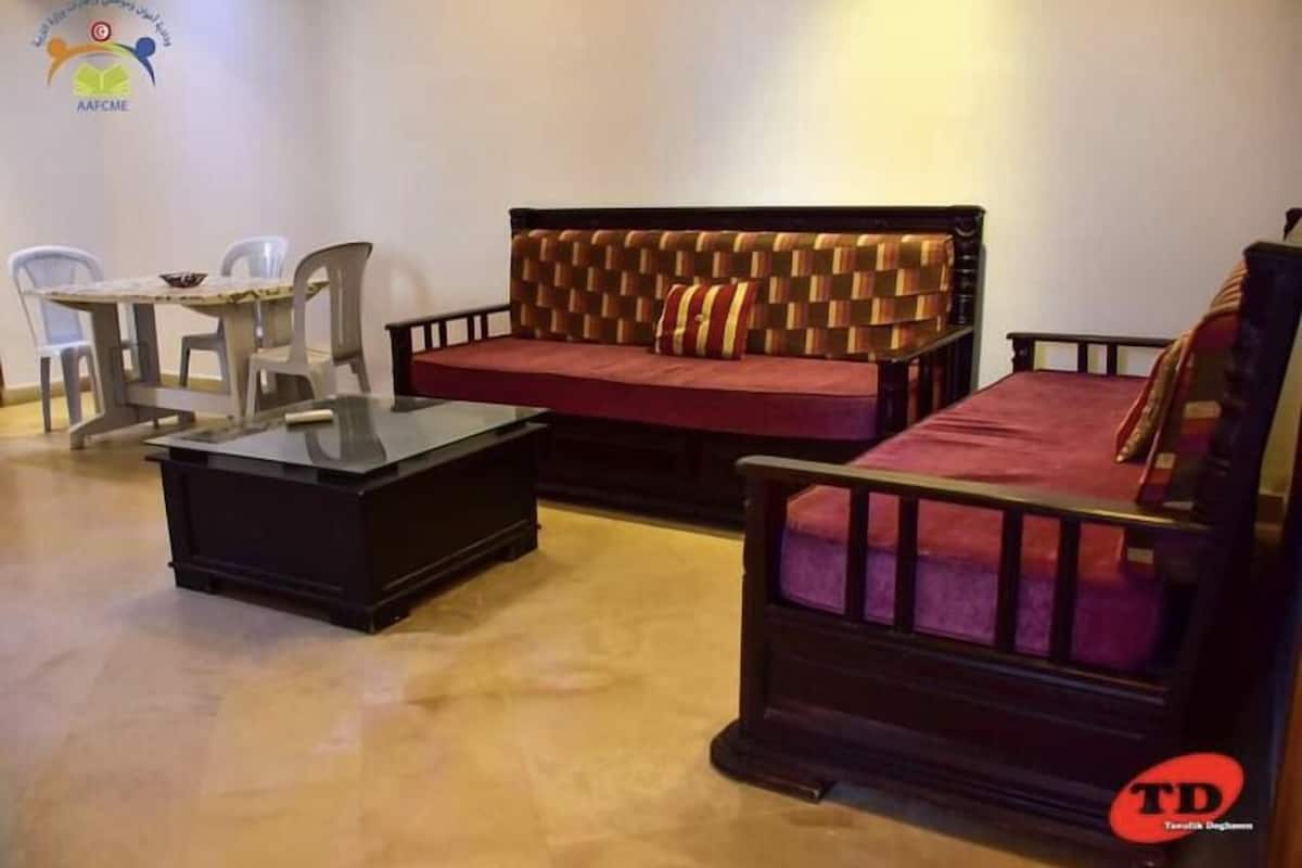 A furnished living room with a sofa, a coffee table, and a small table with chairs.