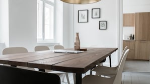 A dining area with a wooden table, chairs, a laptop, and framed botanical prints on the wall. - 3 Bedroom Apartment in Latin Quarter (Copenhagen)