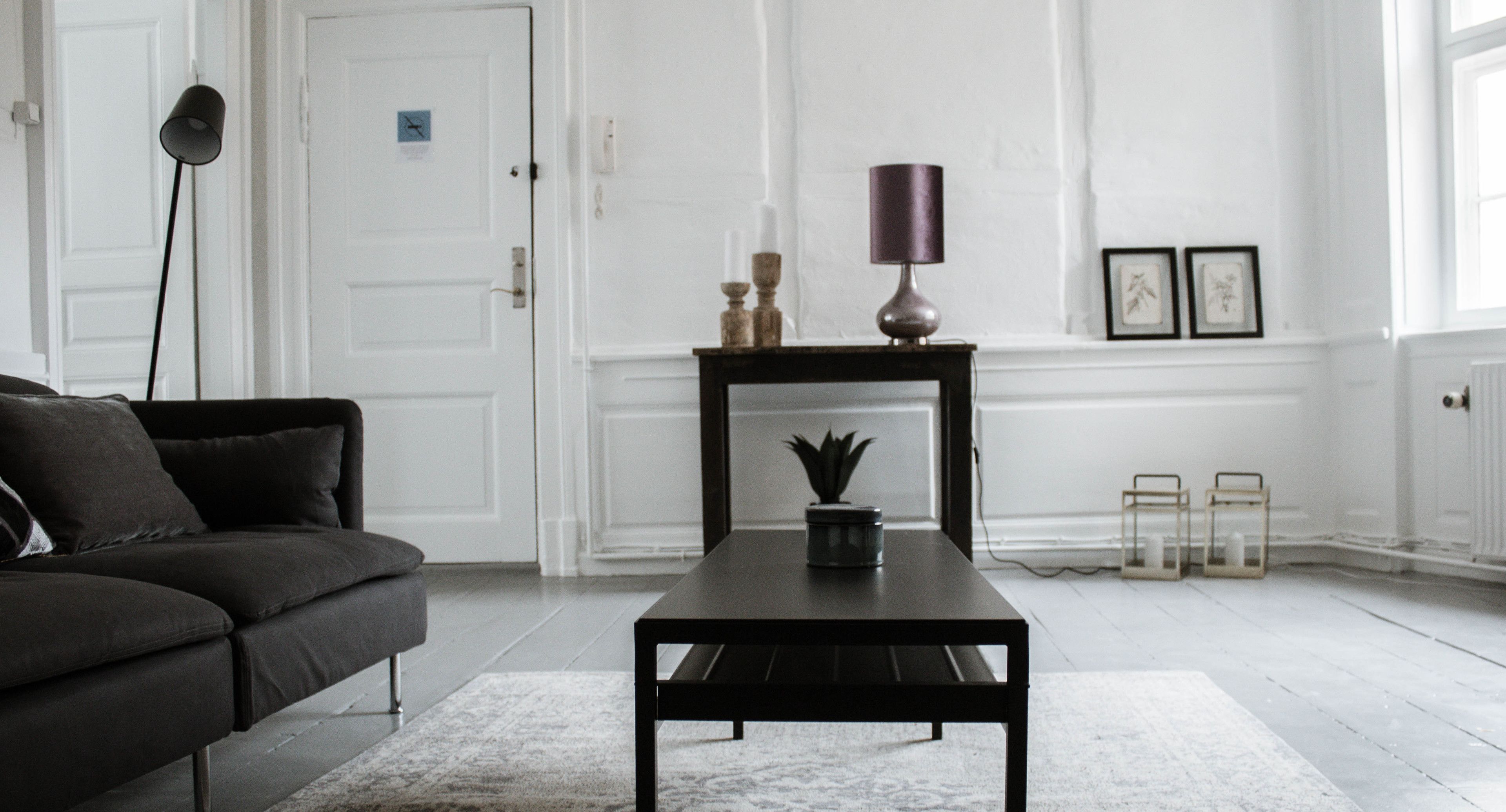 En moderne stue med en mørk sofa, et sort sofabord og en lampe.