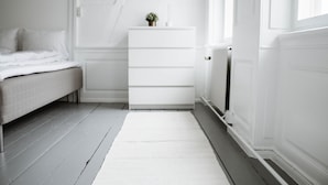 A bedroom with a bed, a dresser, and a radiator. - 3 Bedroom Apartment in Latin Quarter (Copenhagen)