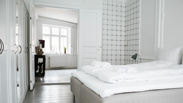 A hotel room with a large bed, a bathroom with a tiled wall, and a hallway leading to another room. - 3 Bedroom Apartment in Latin Quarter (Copenhagen)