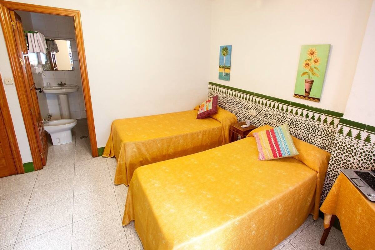 Une chambre d’hôtel avec deux lits, une salle de bain et une petite table avec un ordinateur portable.