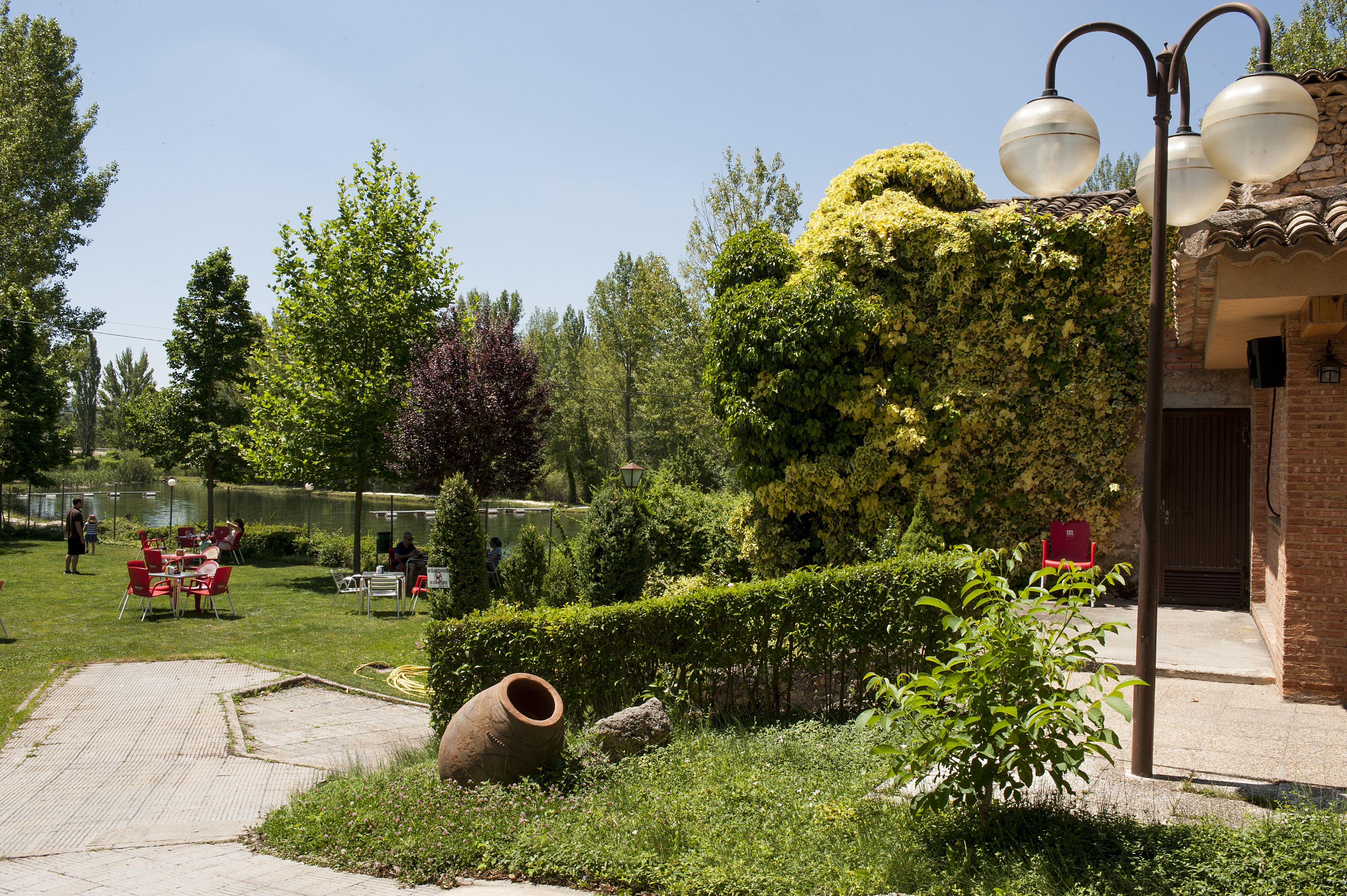 Un jardín con patio, mobiliario exterior y un edificio de ladrillo.