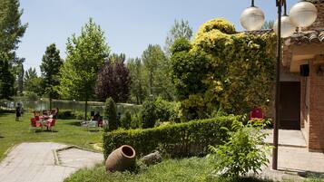 Un jardín con patio, mobiliario exterior y un edificio de ladrillo.