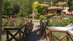A wooden bridge over a stream leading to a building with a tiled roof. - Hotel Restaurante El Tablazo (Villalba de la Sierra)