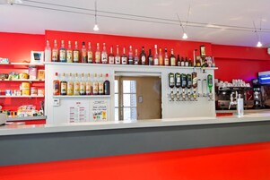 Una zona de bar con estantes llenos de botellas de licores, una máquina de café y una pizarra con el menú.