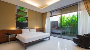 Habitación de hotel moderna con una cama grande, una zona de estar y vistas a zonas verdes a través de la puerta de cristal.