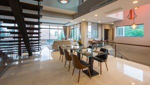 Un interior moderno con comedor, escalera y ventanas amplias.