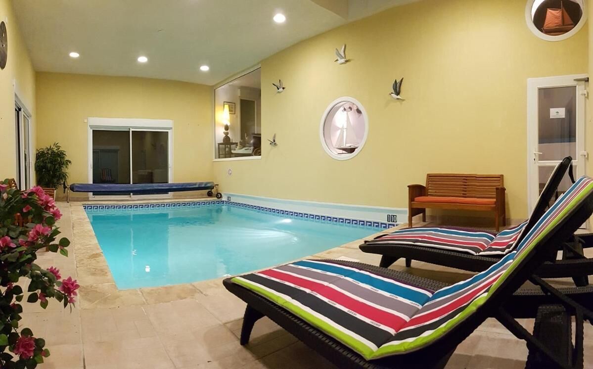 A swimming pool with lounge chairs, a bench, and a door.
