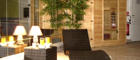 A spa area with a wooden sauna, a large bamboo plant, wicker furniture, and a fire extinguisher on the wall.
