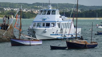 A white boat with blue trim and the name "ENEZ - VAZ" on its side, docked at a pier with other boats.