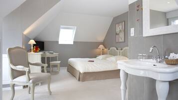 A bedroom with a large bed, a desk, a chair, a vanity with a sink, and a window.