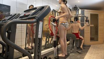 Ein Fitnessstudio mit Laufbändern, Kraftgeräten und einer Spiegelwand.