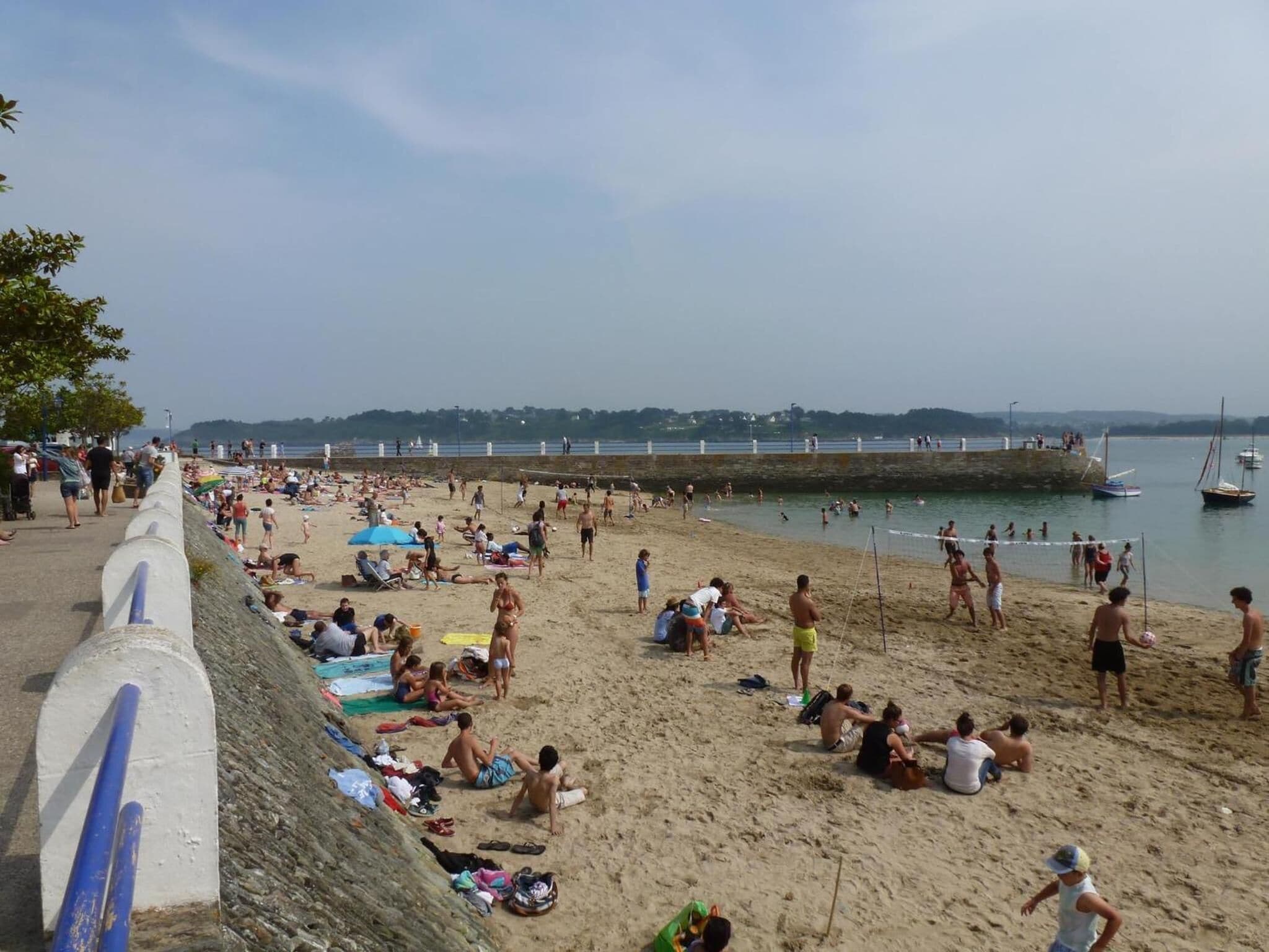 Ein voller Strand mit Menschen, die sich sonnen und Volleyball spielen.