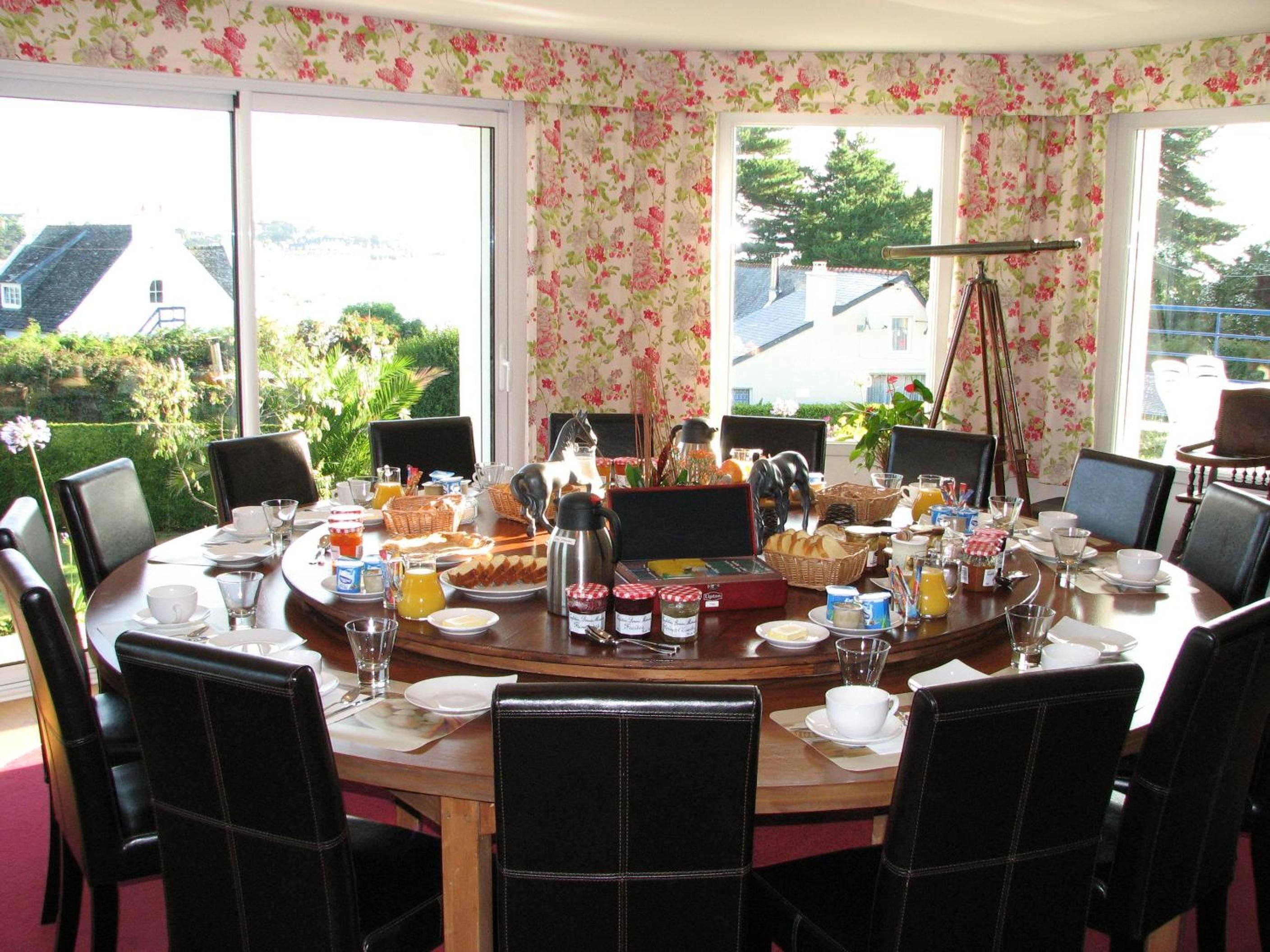 A dining area with a round table set for breakfast, surrounded by chairs.