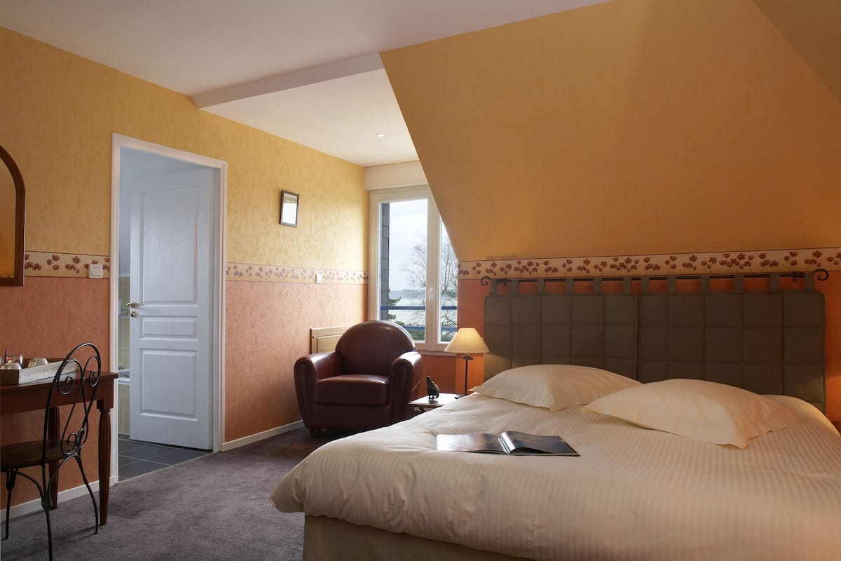 Habitación de hotel con cama, escritorio, silla y ventana.