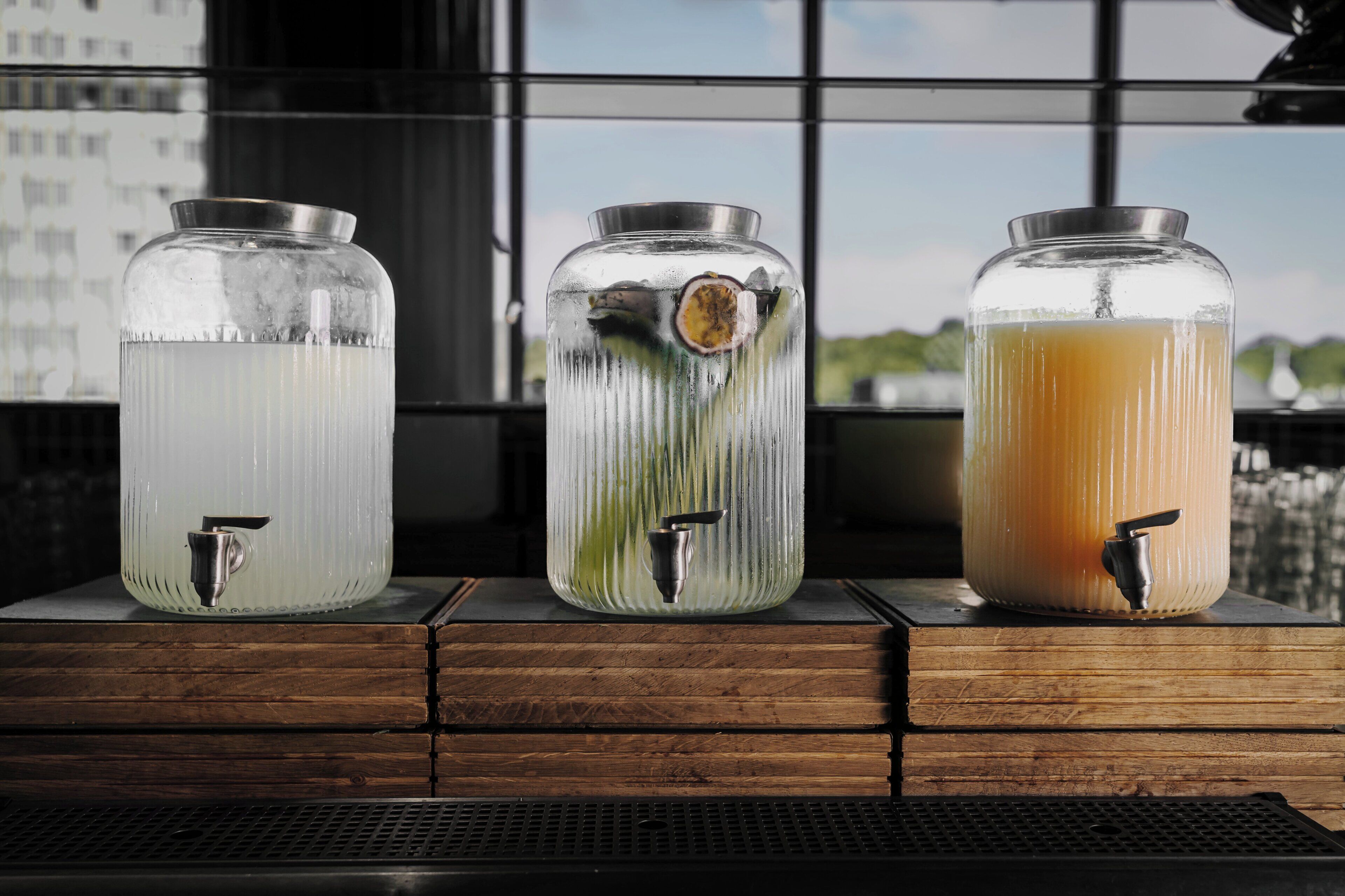 Three glass dispensers with taps on a wooden surface.