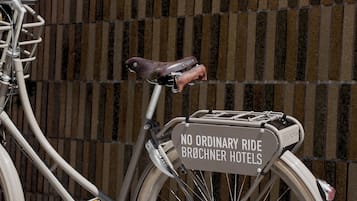 A bicycle with a sign on the rear that reads "NO ORDINARY RIDE BROCHNER HOTELS".
