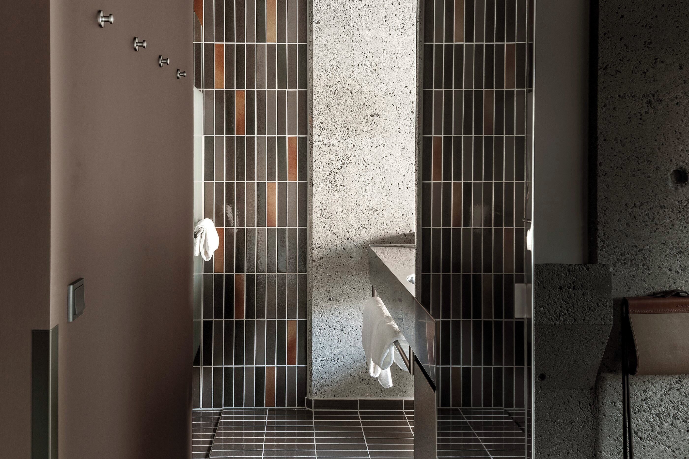 Un baño moderno con piso de baldosas, una columna central y un perchero.